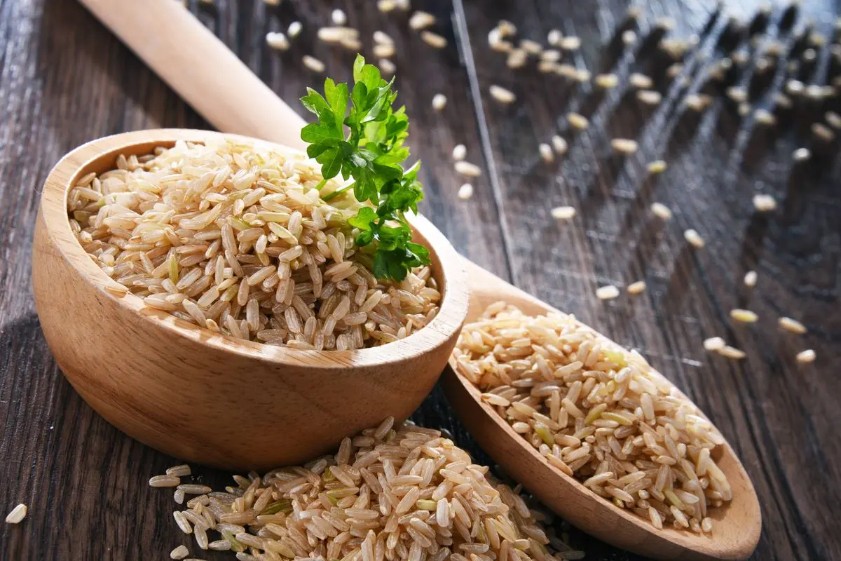 چشمه برنج قهوهای در ظرف چوبی روی میز چوبی