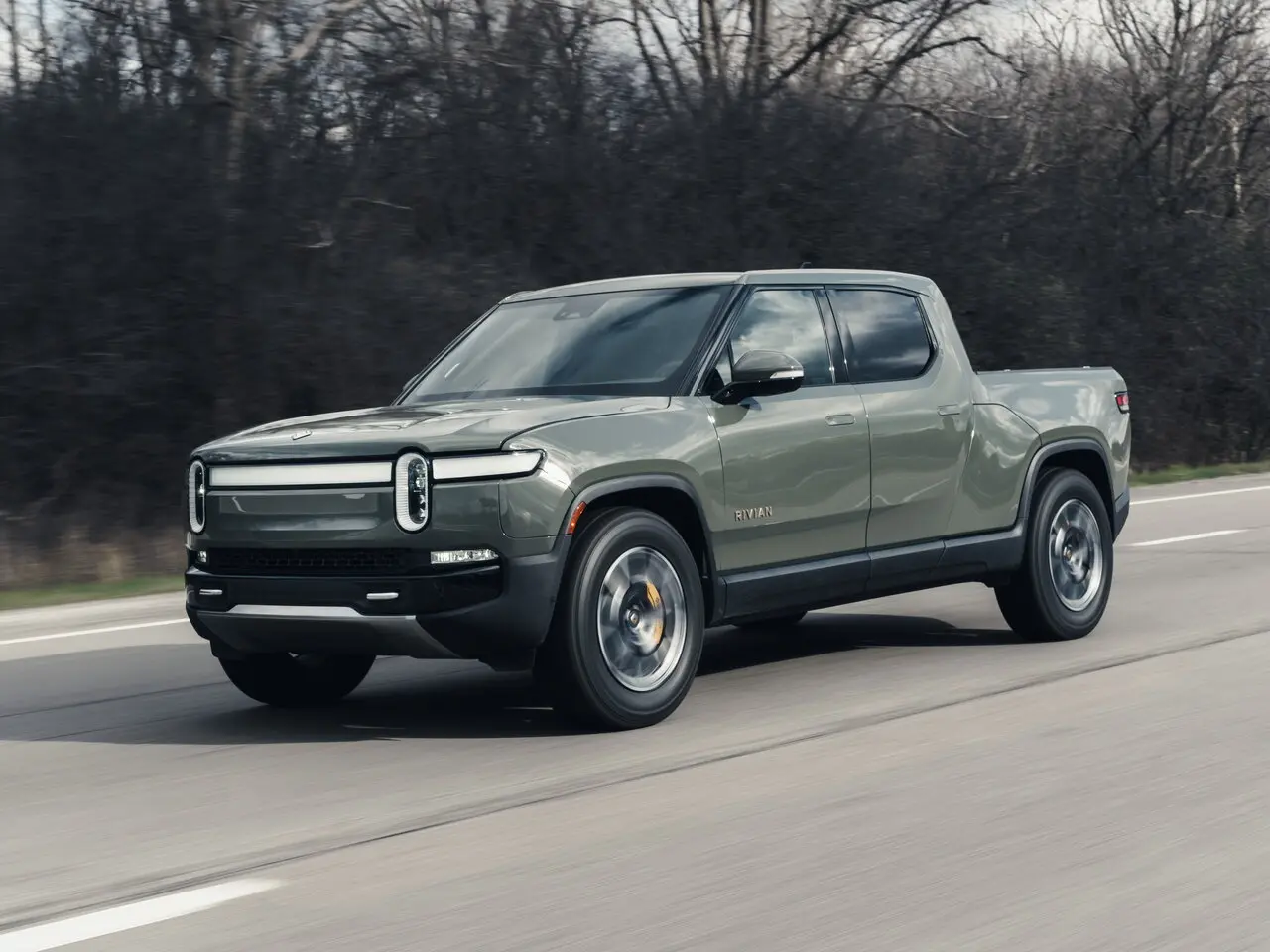 Rivian R1T در حال حرکت در مسیر آفرودی با سیستم تعلیق فعال و چراغ‌های روشن