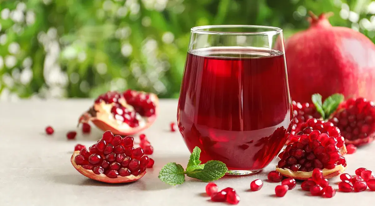 انار تازه و آب انار طبیعی در ظرف شیشه‌ای