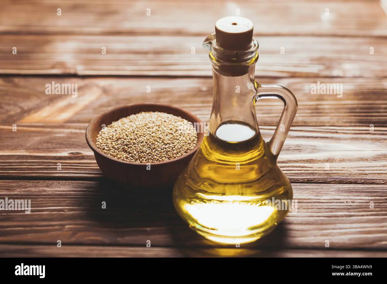 بوتلی شیشهای روغن کنجد با یک کاسه چوبی پر از دانه کنجد