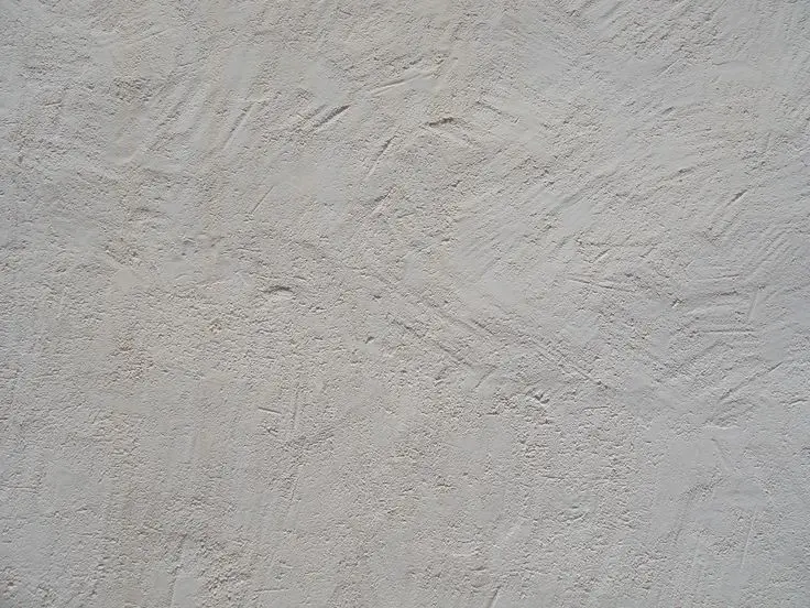 کارگر در حال اعمال گچ ساتن بر روی دیوار با اسپاتول