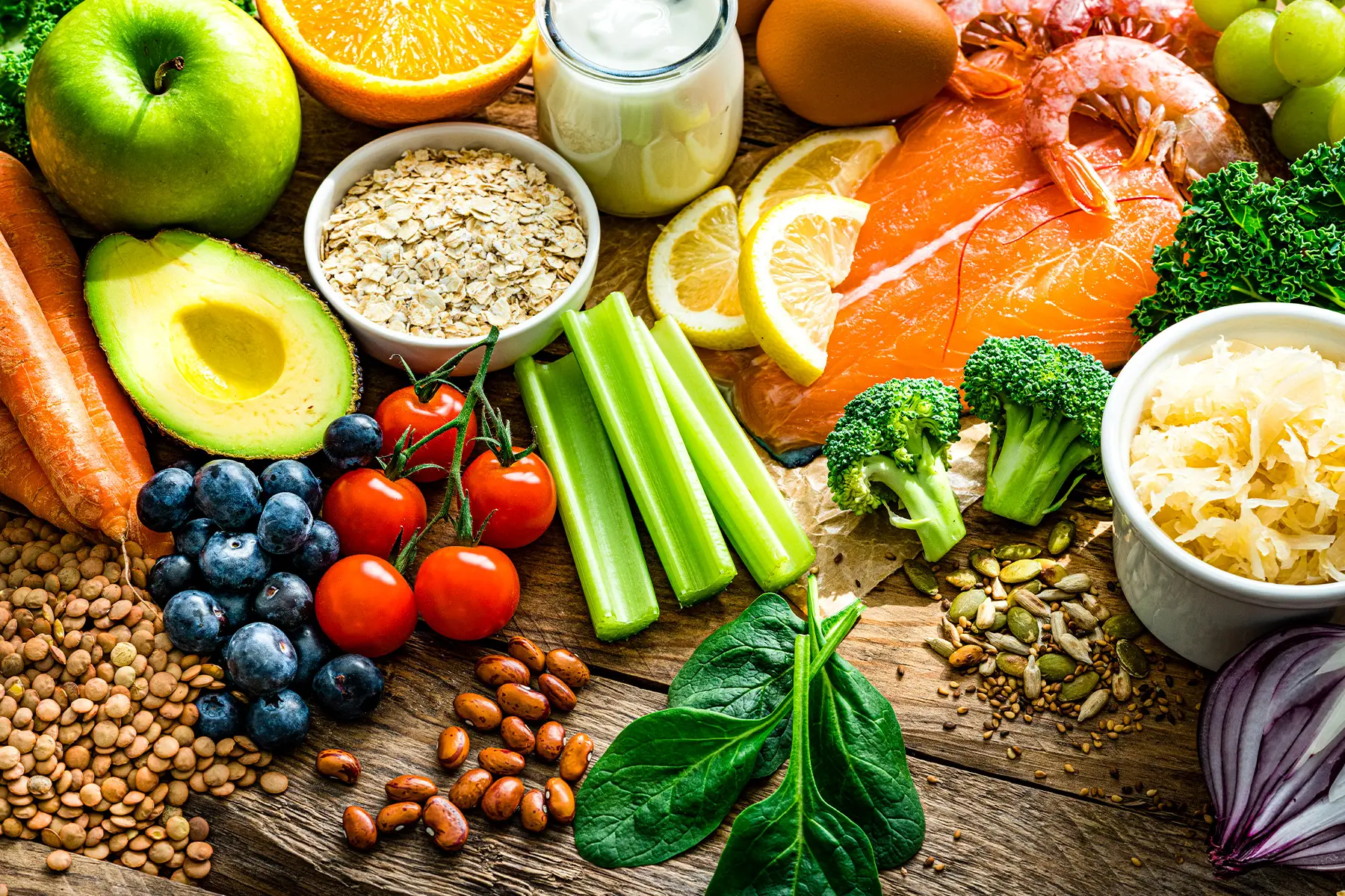 یک میز غذا با مواد غذایی سالم و متنوع مانند میوه، سبزی، غلات کامل و پروتئین‌های سالم