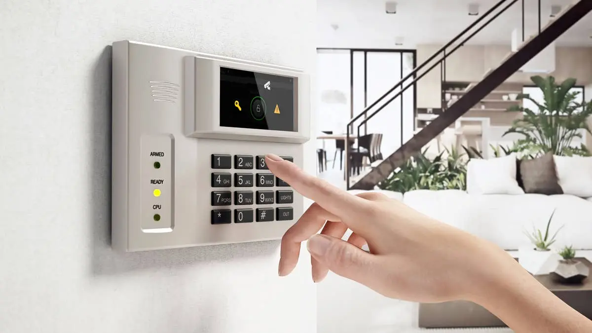 یک فرد در حال وارد کردن کد امنیتی بر روی کیپاد دیجیتال سیستم دزدگیر در یک اتاق نشیمن مدرن